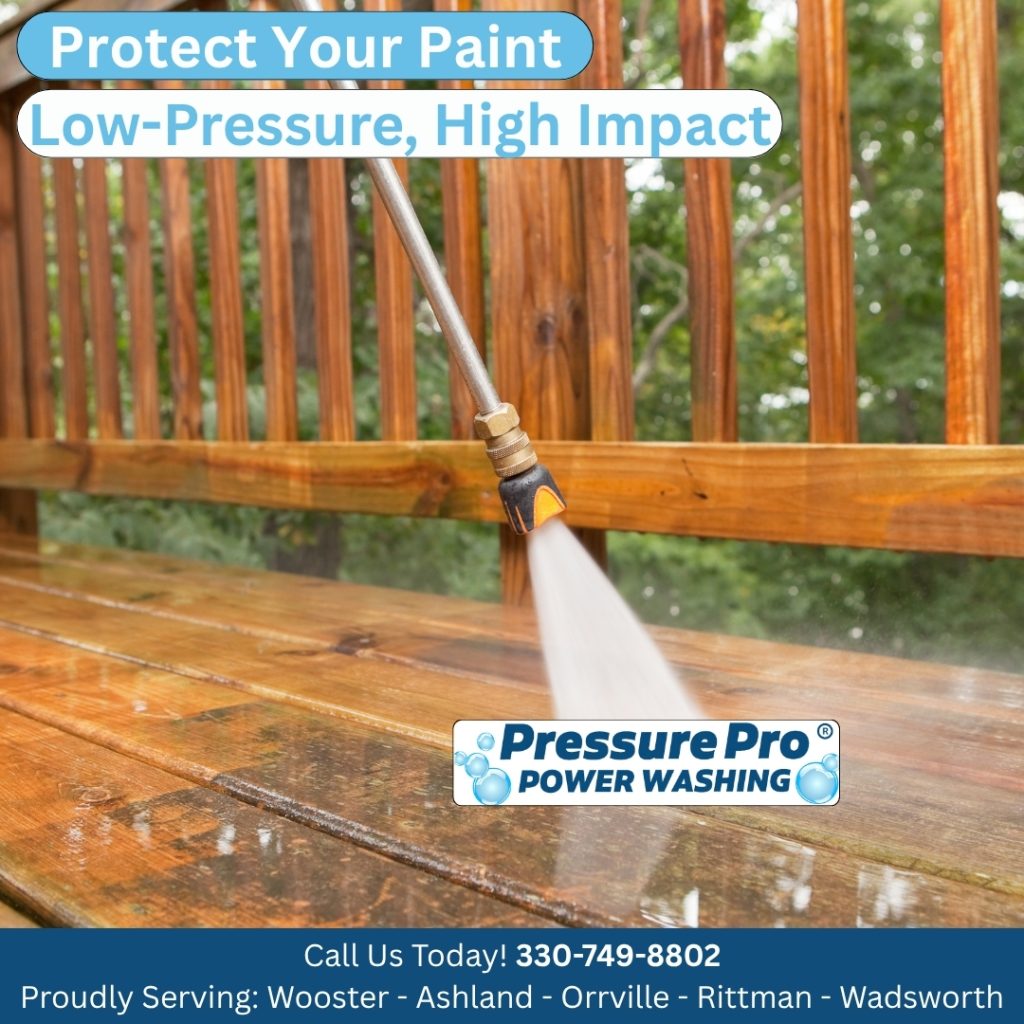 A close-up view of a power washing wand spraying water onto a wooden deck to clean and protect the surface. The image includes promotional text for Pressure Pro Power Washing.